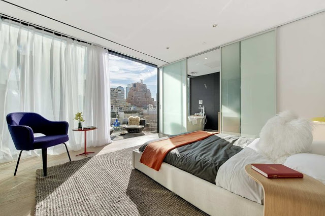 modern master bedroom with glass wall, sliding door, wood floor and orange and purple accents