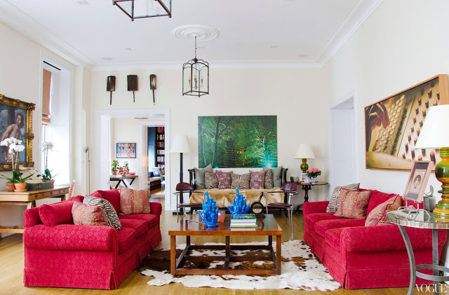 Apartment living room with red dueling sofas, an animal skin rug, a wooden coffee table, high ceilings and two pendant lights