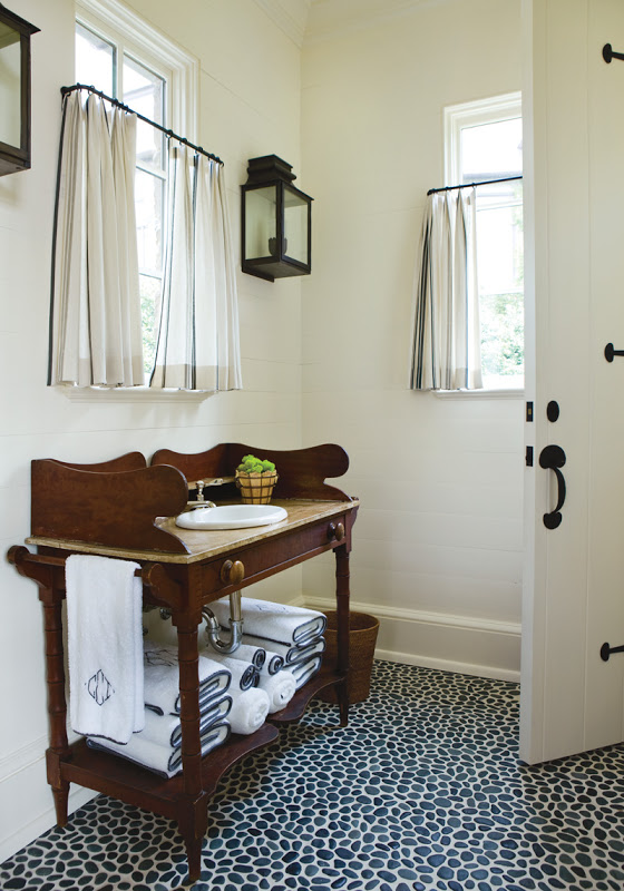 Bathroom with pebble floor, wall mounted lantern and a console sinks made of wood and marble