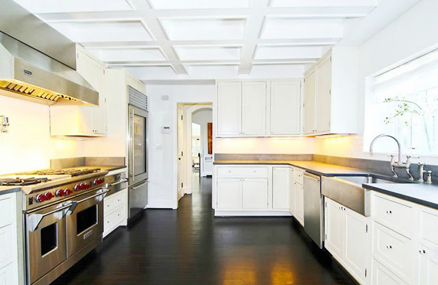 kitchen with a stainless wolf stove and oven, farmhouse sink, white cabinets and wood floor