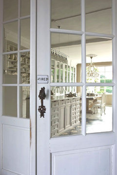 White glass door leading to kitchen with a small sign that says tirez above the knob in a mansion in Belgium