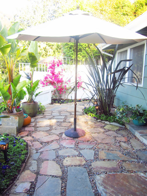 Backyard with umbrella, shrubbery, lanterns and potted plants