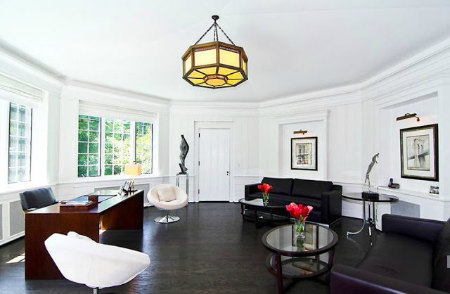 Oval home office with leather furniture, dark wood floors and an octagon pendant light