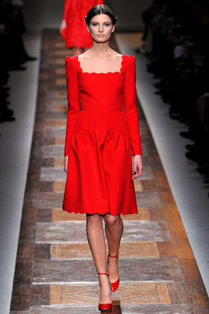 model from valentino fall 2012 runway show wearing a red dress with scalloped hemline and neckline 