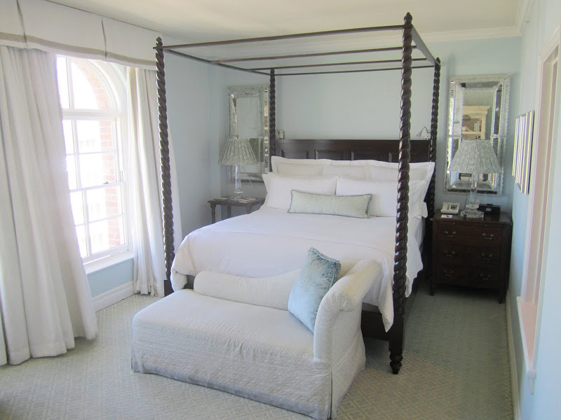 Bed in a Casa del Mar guest room with canopy bed, light blue walls, chest of drawers, mercury mirrors and chaise lounge at the foot of the bed