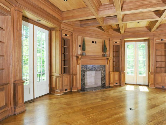 Wood paneled library/home office with french doors, visible beams a fireplace