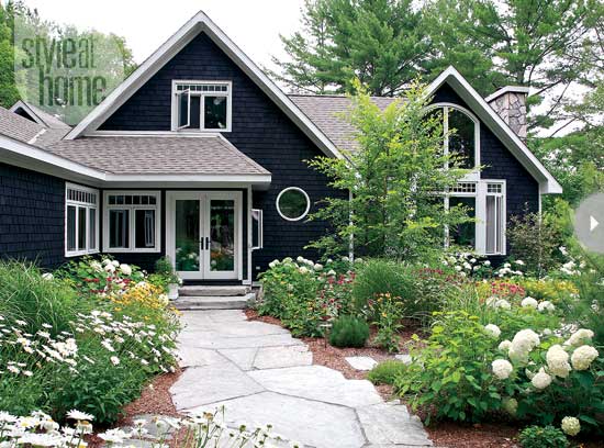 charcoal gray cottage house with white trim flagstone path garden
