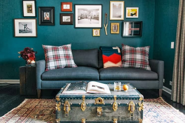 Teal living room with red, white and green Tartan pillows and a trunk with gold detailing doubling as a coffee table