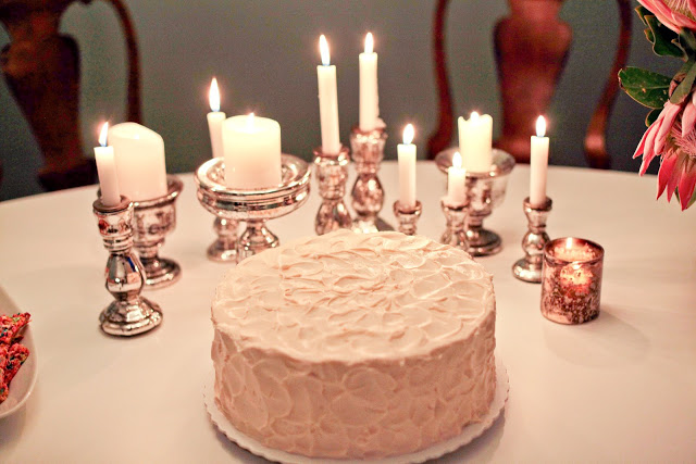 close up of birthday cake surrounded by candles in mercury candlesticks