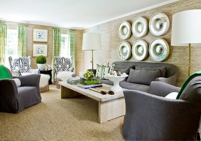 Living room with six rounds mirror arranged on a sea grass walls, reclaimed wood coffee table, grey sofas, gray ikat armchairs and a woven sea grass sisal rug