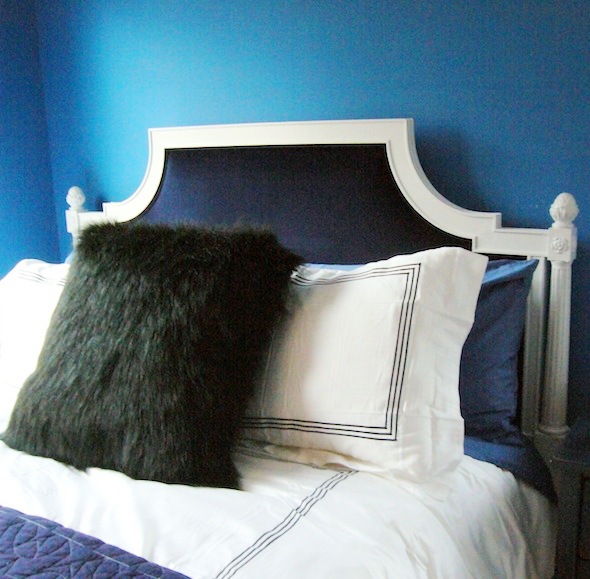The refurbished white and blue velvet headboard in a blue boys room with white sheets with navy piping and a furry accent pillow