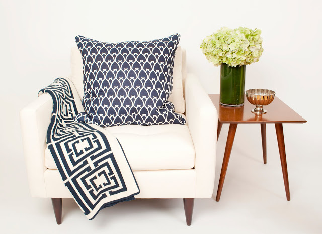 COCOCOZY Logo Throw in navy on a white chair with a COCOCOZY pillow in Navy and a wooden side table with hydrangeas