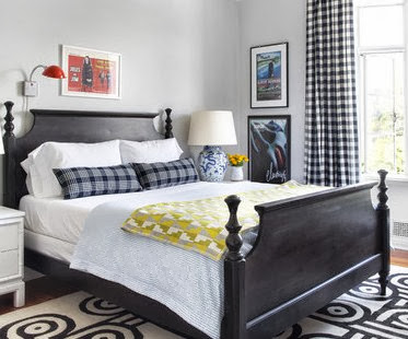 Bedroom with blue plaid pillows, black and white gingham curtains and a dark wood bed with white bedding