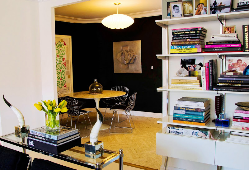 Breakfast nook with black walls, herringbone floor, Saarinen tulip table, Bertoia wire chairs, and an oval pendant light