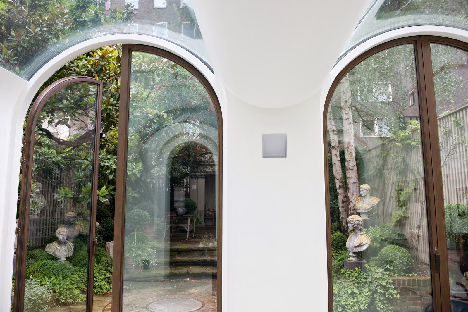 Arched glass doors opening to a garden in a mews townhouse by Andy Martin Architects