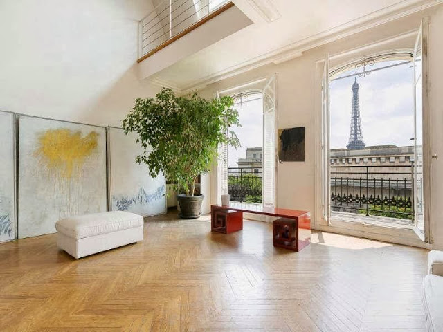 Den in an apartment in Paris, France with herringbone wood floor, french doors with a view of the Eiffel Tower and a Greek key bench
