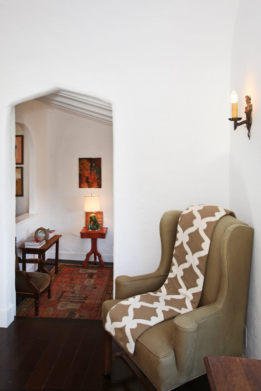 Entryway in a 1920's Spanish style home with a wingback chair and a COCOCOZY Gate throw