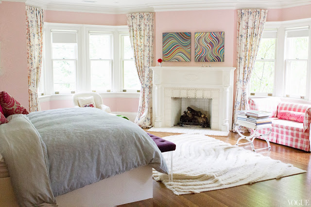 Pink master bedroom in Vogue.com contributor Sophie Young's childhood home with a white fireplace, pink and white gingham sofa and x-bench 