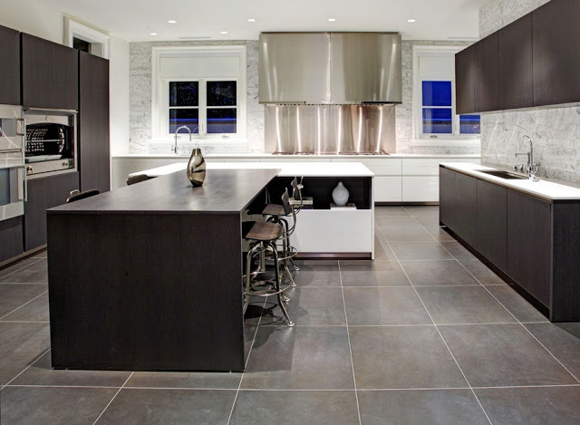 modern kitchen with large square slate tiling, sleek dark wood cabinets, a stainless steel hood and blacksplash cover