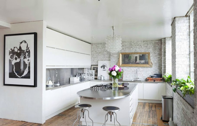 kitchen with exposed brick, sleek white cabinets and an island with metal countertop and white drawers with long pull 