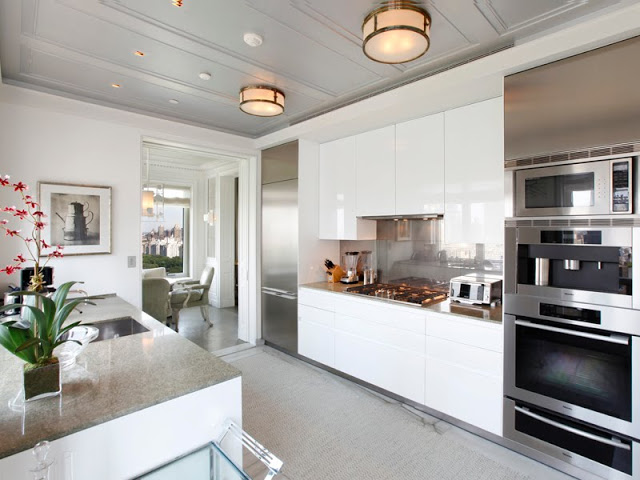 sleek kitchen outfitted with many modern conveniences: stainless appliances, glossy white cabinets and an island