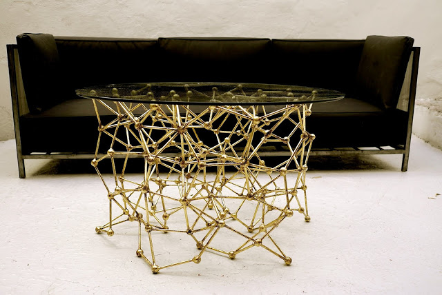 Molecular Coffee Table with gold leaf finish in front of a black sofa