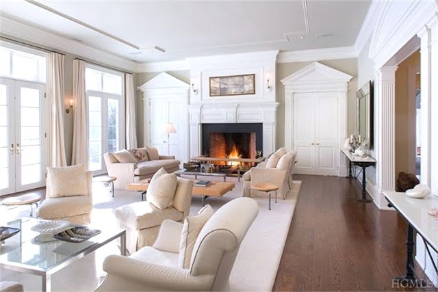 Classic living room in a Bedford, NY home with cream colored armchairs, dueling sofas and hard wood floor