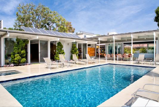 Backyard with a large pool, lounge chairs and a view into the house thanks to glass walls