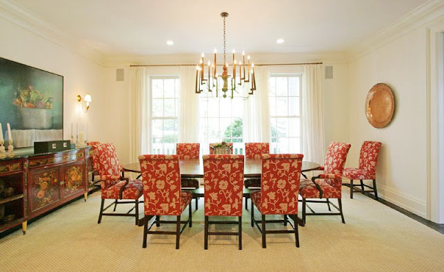 formal dining room with red upholstered chairs, an oval table, a chandelier, french doors with white curtains and traditional decor
