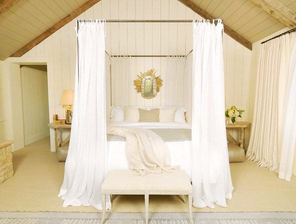 rustic country bedroom with canopy bed, visible beams, two reclaimed wood nightstands and floor length curtains