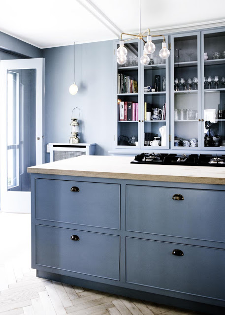 close up of blue cabinets in an entirely blue kitchen with herringbone wood floors