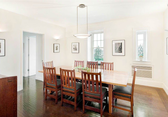 dining room with long wood table, wooden chairs, a pendant light, white walls and framed pictures