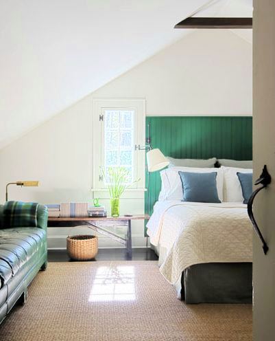 bedroom with sisal rug beadboard, green headboard, a green leather sofa with a plaid throw, dark wood floor, a bench style nightstand and a small window