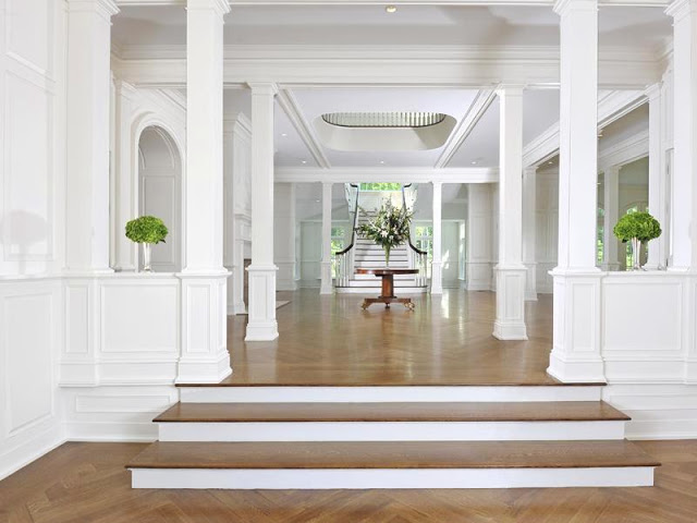 alternative view of the foyer with white grand staircase, fire place and herringbone wood floor