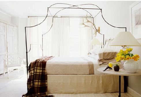 modern rustic bedroom with canopy bed, wood floors, a plaid throw and white floor length curtains