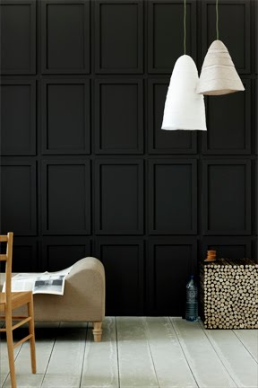 Dark living room with black paneled walls white pendant light grey wood floor