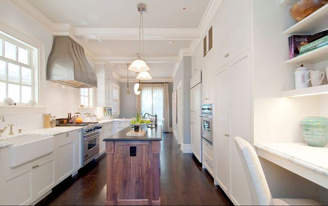 Kitchen with white cabinets, wood stained island, pendant lights and dark wood floor