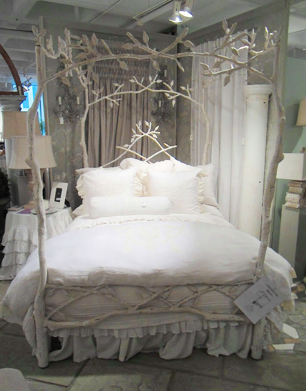 An iron bed frame made to look like tree branches. The bedding is white and very romantic from Pom Pom at Home designed by Hilde Leiaghat.