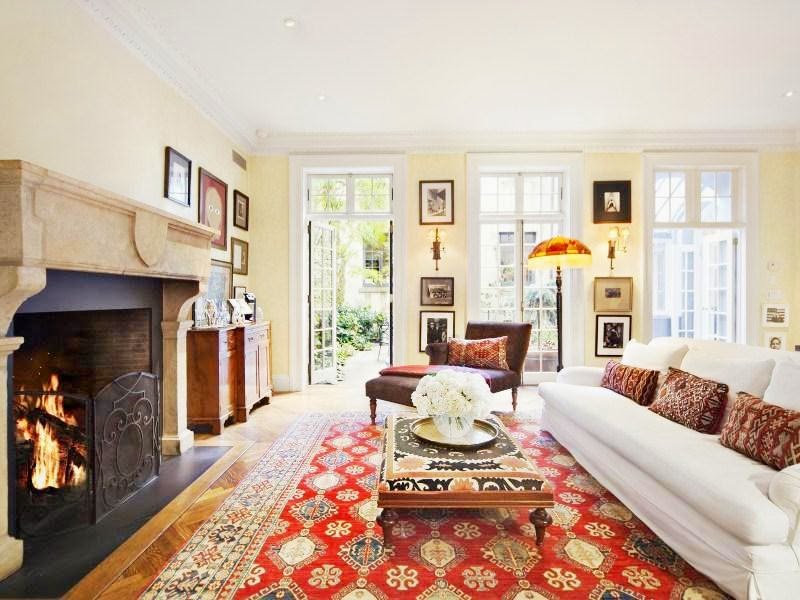 Living room in a NYC home with white sofa, Persian rugs, herringbone wood floor and marble fireplace