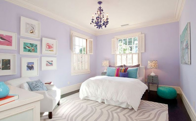 Girls bedroom with small chandelier, lavender wall, grey and white zebra print rug, white bedding with colorful accent pillows