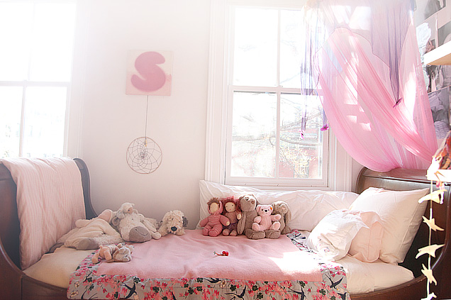 traditional wood sleigh bed with pink bedding in a girl's room with a pink canopy and white window