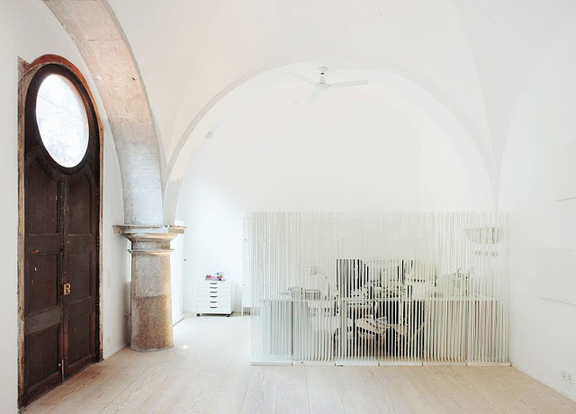 cloister in Barcelona turned into a living room with screen dividers to separate the office from the rest of the room