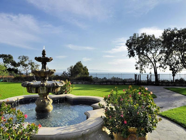 Ocean view from the backyard with a traditional fountain, a lawn and potted plants