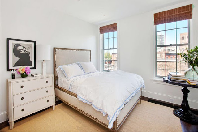 cozy guest room with upholstered headboard, white chest of drawers, two windows and a black desk