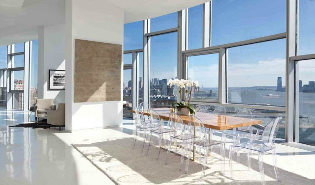 Dining room with Louis Ghost Chairs, wood table and huge windows with a great view of NYC