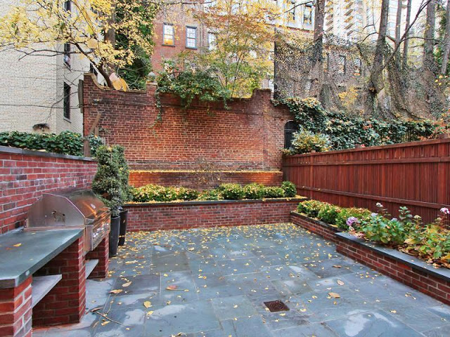 Ground level garden with brick walls, grill and built in planters with flowers