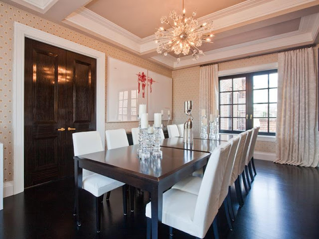 Dining room in an apartment with coffered ceiling, dark wood floors, sputnik starburst chandelier, contemporary print wallpaper, black encasement windows with floor length curtains, dark wood double doors, and a piece of modern art