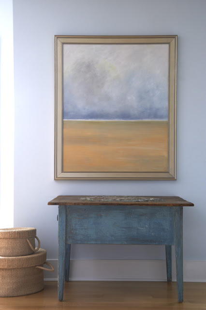 Painted wood console table with a painting hanging on a blue grey wall