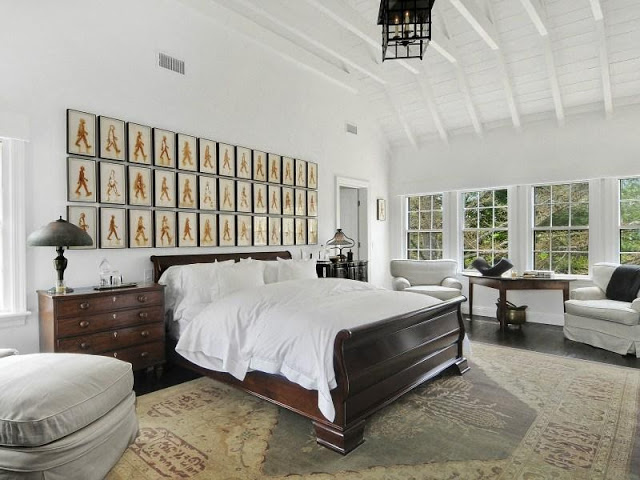 Bedroom in an East Hampton compound with a gallery wall, wood floor and lantern lamp