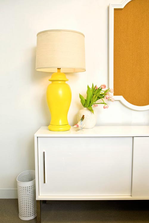 Office with white cabinet with sliding door with a long drawer pull, a yellow lamp and a pot of tulips